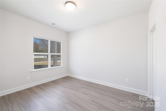 unfurnished room featuring visible vents, baseboards, and wood finished floors