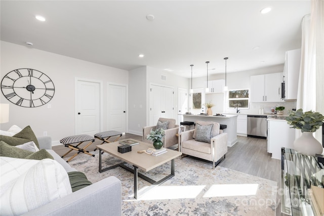 living room with light wood finished floors, visible vents, recessed lighting, and baseboards