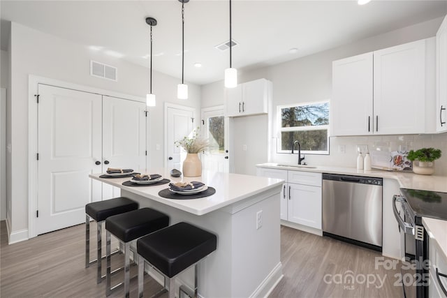 kitchen with visible vents, white cabinets, dishwasher, and a sink