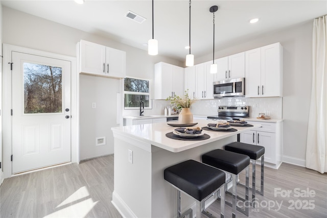 kitchen featuring visible vents, white cabinets, stainless steel appliances, and light countertops