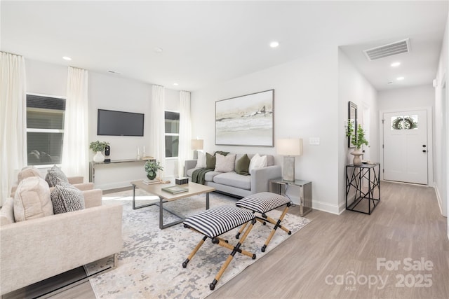 living area featuring visible vents, baseboards, recessed lighting, wood finished floors, and plenty of natural light