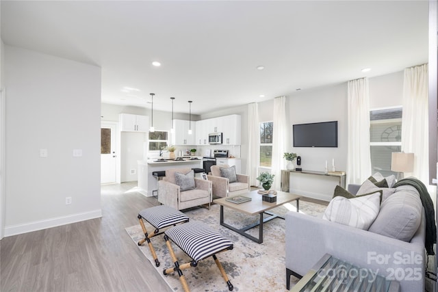 living area with light wood finished floors, recessed lighting, and baseboards