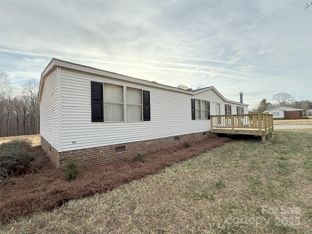 view of property exterior with crawl space, a wooden deck, and a lawn