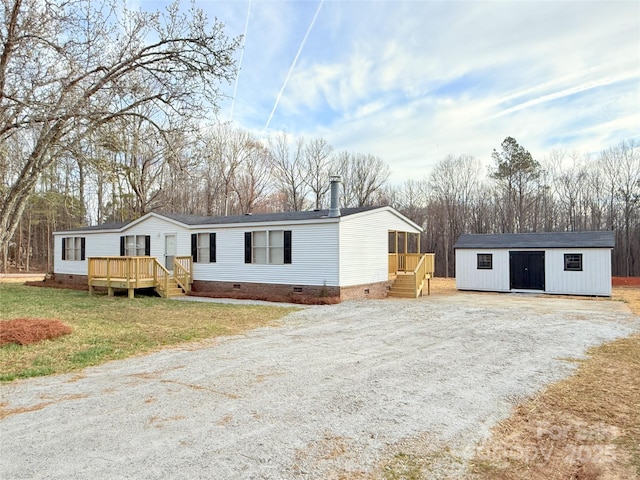 manufactured / mobile home with an outbuilding, driveway, crawl space, a wooden deck, and a front yard