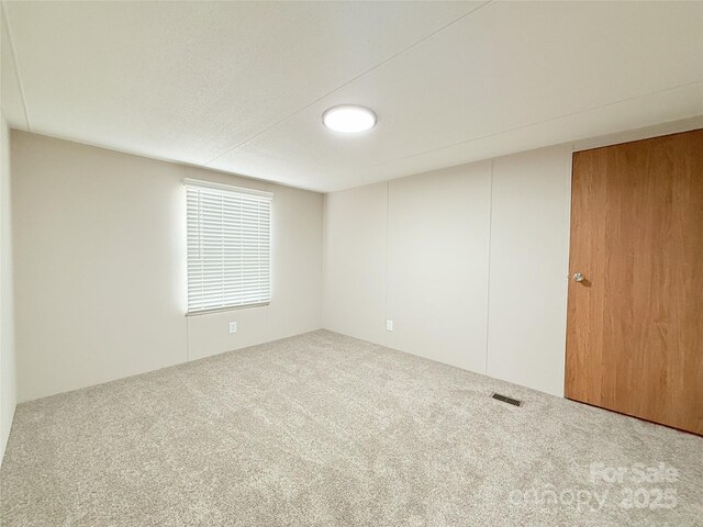 carpeted spare room featuring visible vents