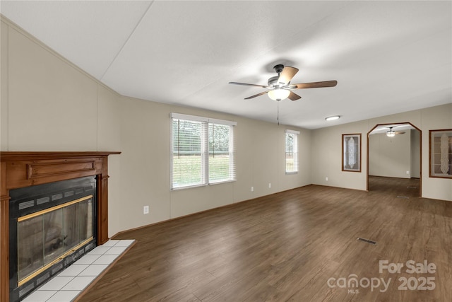 unfurnished living room with a ceiling fan, a tile fireplace, and light wood-type flooring