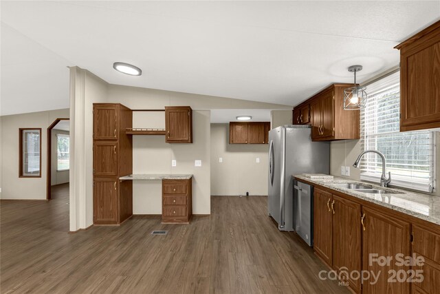 kitchen with lofted ceiling, dark wood-style flooring, a sink, appliances with stainless steel finishes, and brown cabinets