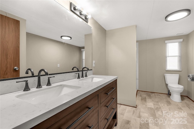 full bath featuring toilet, a sink, double vanity, and visible vents