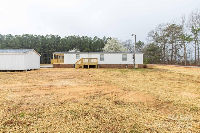 back of property featuring an outdoor structure, crawl space, a shed, and a wooden deck