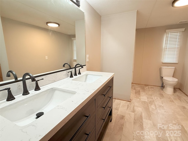 bathroom featuring toilet, a sink, double vanity, and visible vents