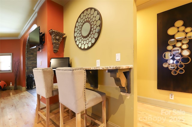 dining room with ornamental molding, baseboards, and light wood finished floors