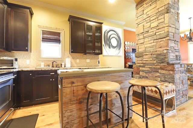 bar with backsplash, electric range, an inviting chandelier, ornamental molding, and light wood-type flooring