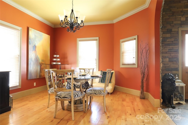 dining room with light wood-style floors, baseboards, ornamental molding, and an inviting chandelier