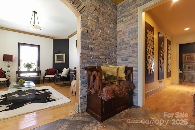 interior space featuring ornamental molding, arched walkways, baseboards, and wood finished floors