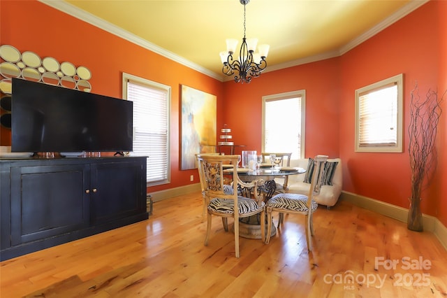 dining space featuring light wood-type flooring, crown molding, baseboards, and an inviting chandelier