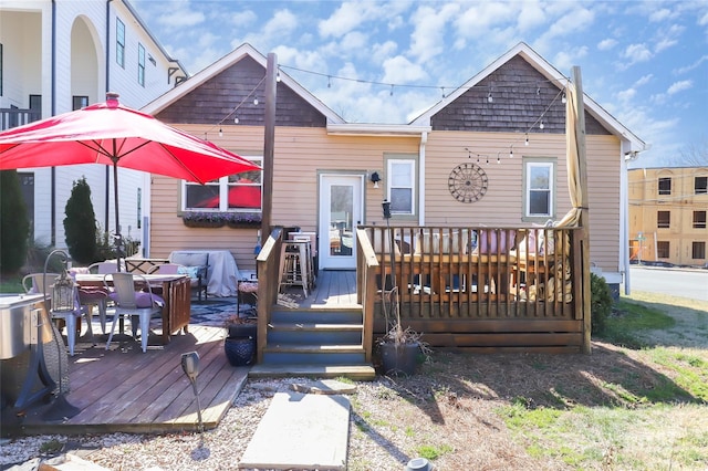 back of property with outdoor dining space and a wooden deck