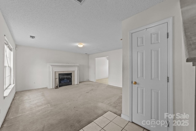 unfurnished living room with visible vents, carpet floors, a textured ceiling, and a fireplace