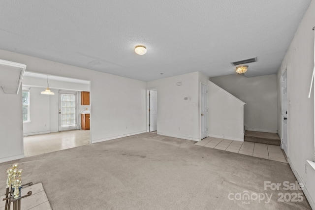 unfurnished living room with visible vents, carpet floors, and a textured ceiling