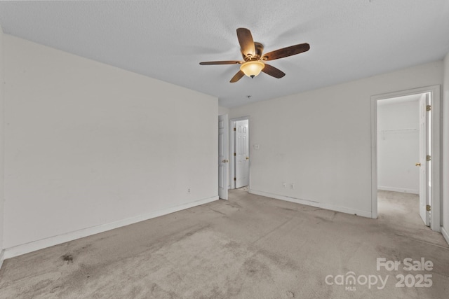 unfurnished room with a textured ceiling, baseboards, carpet floors, and ceiling fan