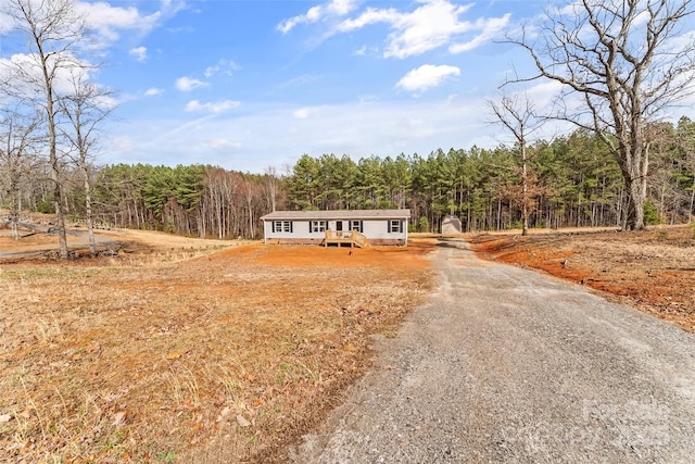 view of front of property featuring driveway and a forest view