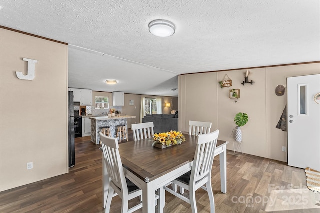 dining area featuring dark wood-type flooring and a textured ceiling