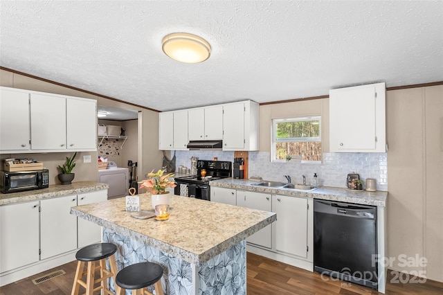 kitchen featuring visible vents, washer / clothes dryer, under cabinet range hood, black appliances, and a sink