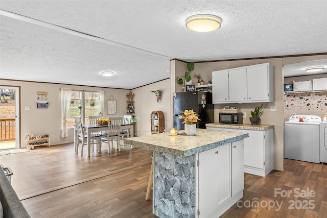 kitchen with white cabinetry, light countertops, dark wood-style floors, black appliances, and washing machine and clothes dryer