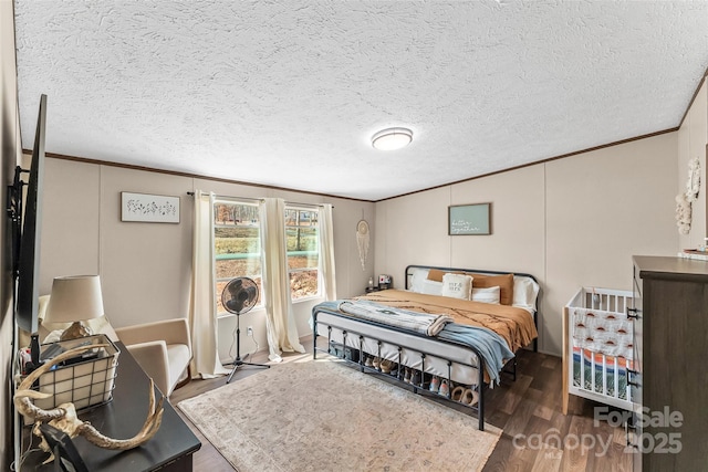 bedroom with a textured ceiling, wood finished floors, and crown molding