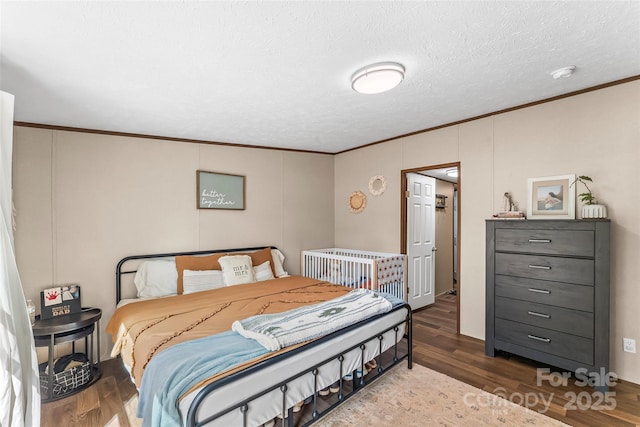 bedroom with a textured ceiling, wood finished floors, and crown molding