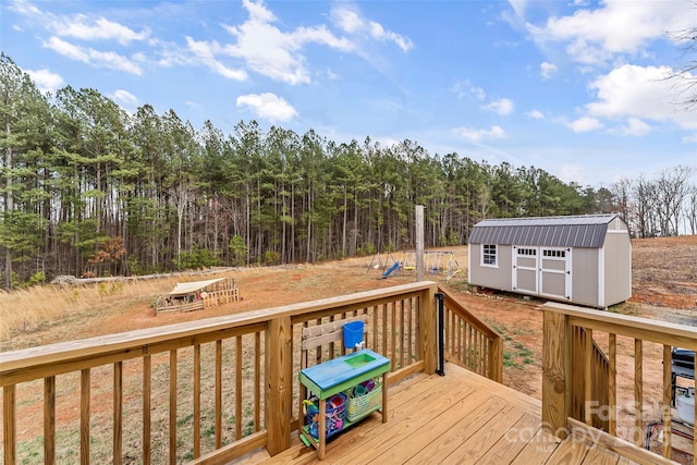 deck with an outdoor structure, a view of trees, and a storage unit