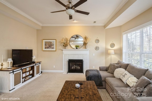 living area with baseboards, carpet floors, a tiled fireplace, and crown molding