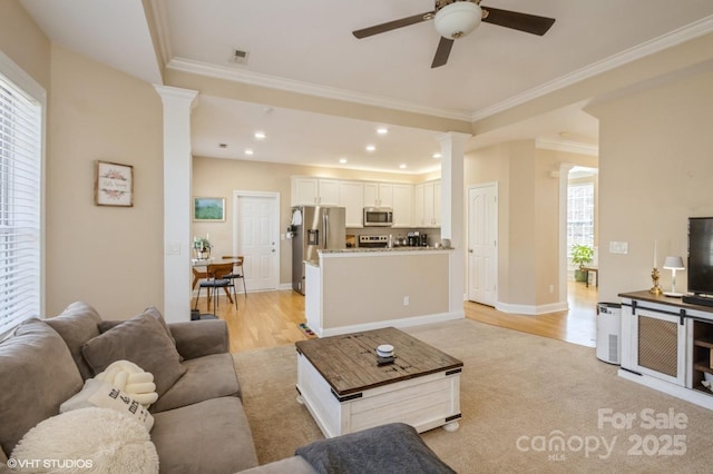 living area featuring recessed lighting, visible vents, baseboards, ornamental molding, and ornate columns