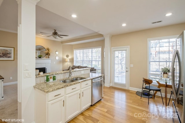 kitchen featuring visible vents, appliances with stainless steel finishes, open floor plan, a sink, and light stone countertops