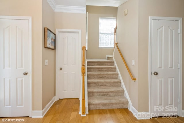 stairs featuring ornamental molding, wood finished floors, and baseboards