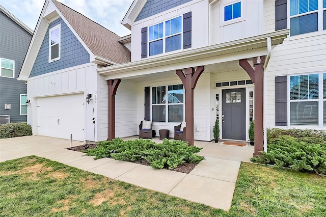 view of exterior entry with driveway, an attached garage, central air condition unit, a porch, and board and batten siding