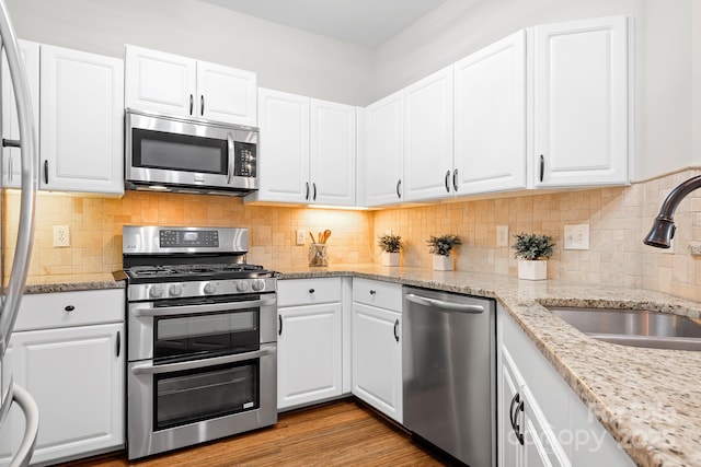 kitchen with appliances with stainless steel finishes, white cabinetry, a sink, and decorative backsplash