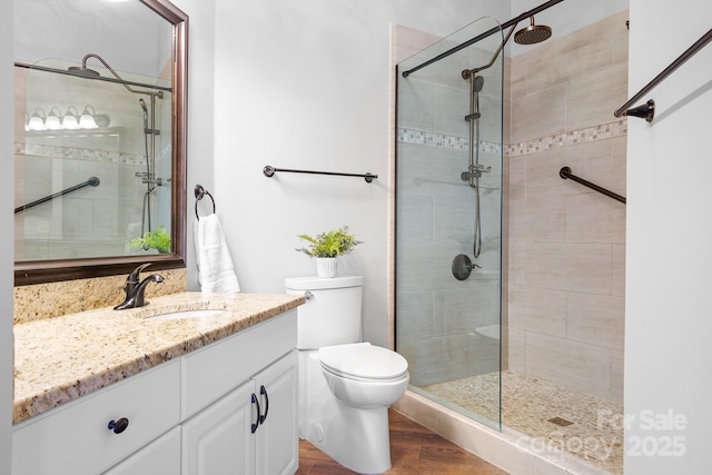 bathroom featuring toilet, a stall shower, and vanity