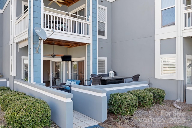 exterior space with ceiling fan, a balcony, and stucco siding