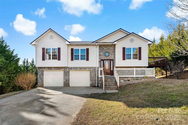 split foyer home with metal roof, a garage, stone siding, driveway, and a front lawn