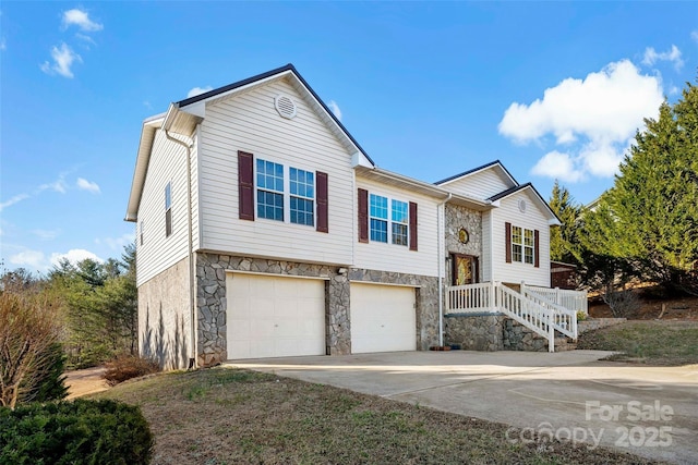 bi-level home with stone siding, driveway, and an attached garage