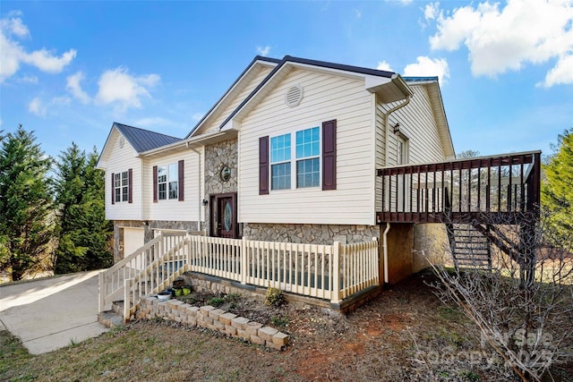 split foyer home with a garage, stone siding, stairway, and metal roof