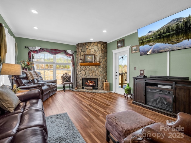 living area with a wealth of natural light, a fireplace, crown molding, and wood finished floors