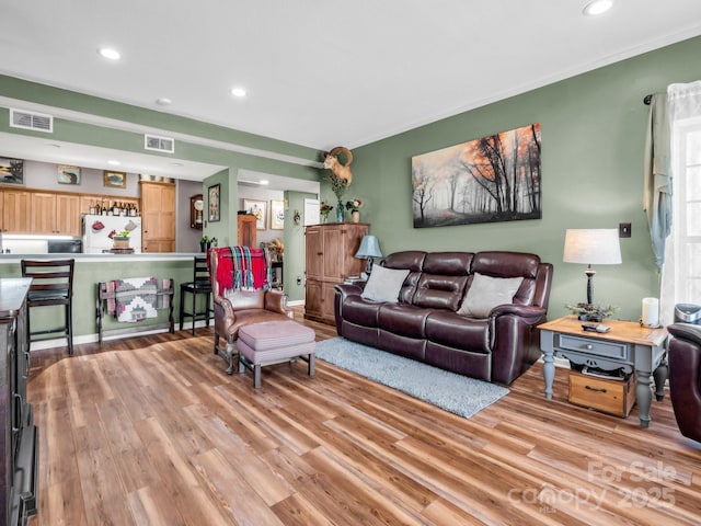 living area featuring recessed lighting, light wood-style floors, and visible vents