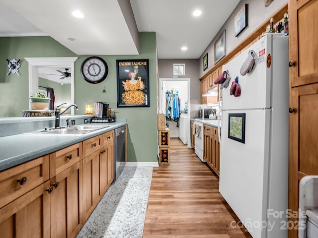 kitchen featuring baseboards, recessed lighting, light wood-style floors, white appliances, and a sink