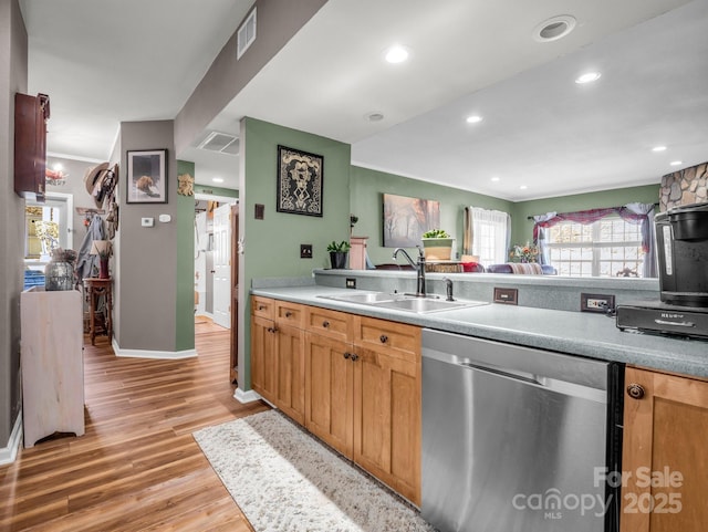 kitchen with visible vents, light wood-style flooring, a sink, stainless steel dishwasher, and light countertops