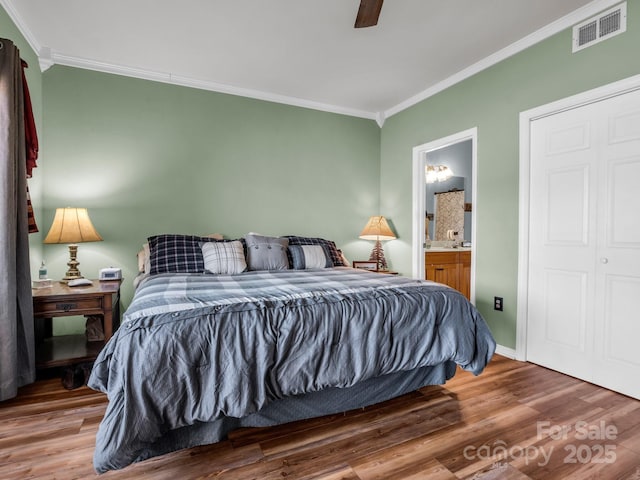 bedroom with visible vents, connected bathroom, ceiling fan, ornamental molding, and wood finished floors