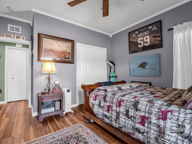 bedroom featuring a closet, visible vents, crown molding, and wood finished floors