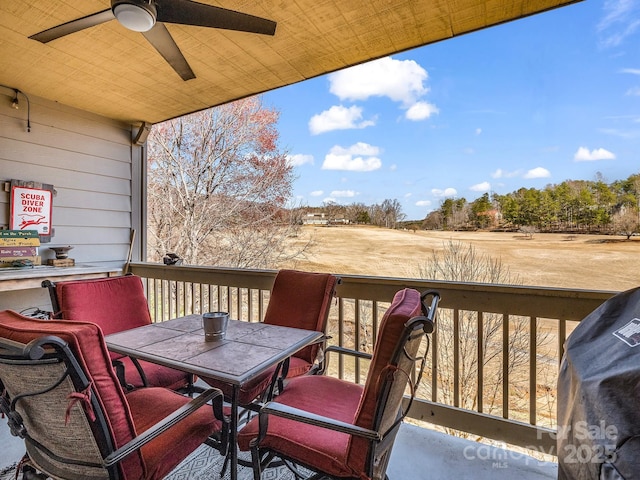 wooden deck featuring outdoor dining area, a ceiling fan, and a grill