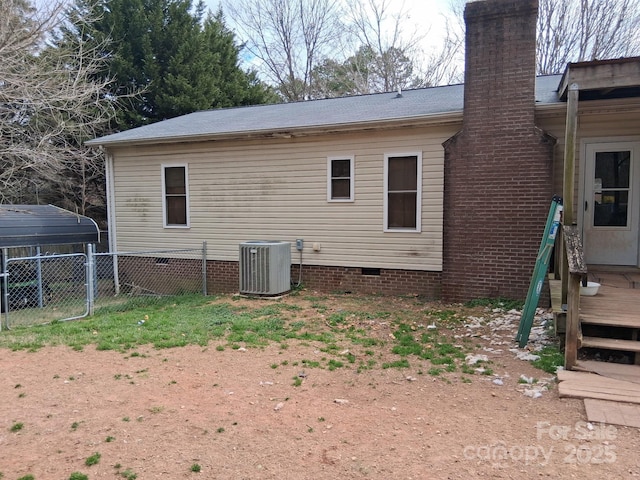 rear view of property featuring crawl space, a chimney, central AC, and fence