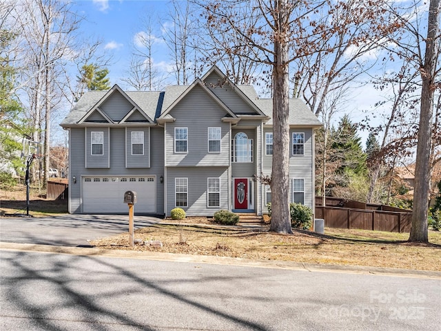 view of front of property with aphalt driveway, a shingled roof, a garage, and fence